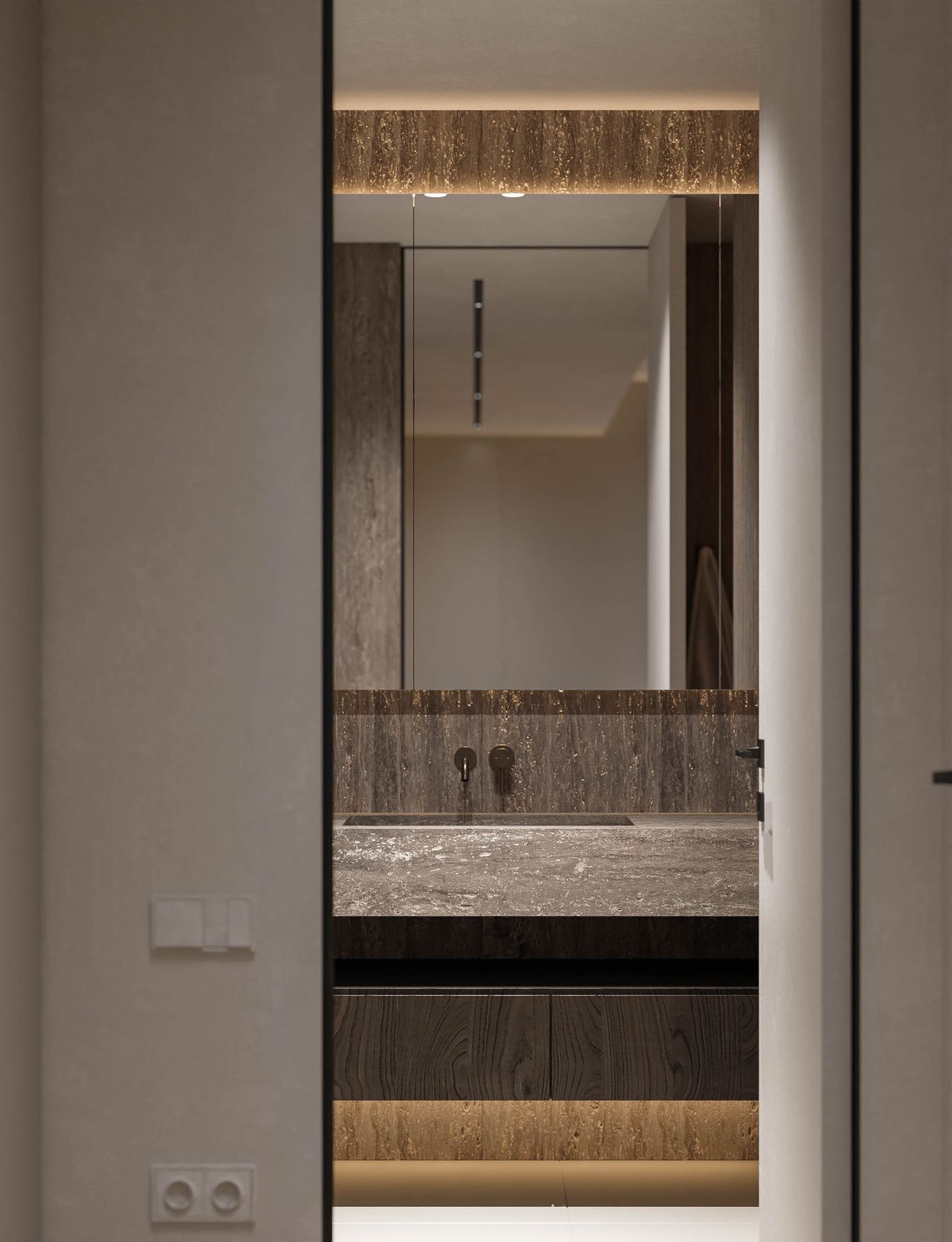 Concept pentru baie, văzută din hol: lavoar cu aspect de travertin, baterie de culoarea bronzului și dulap cu oglindă iluminat.