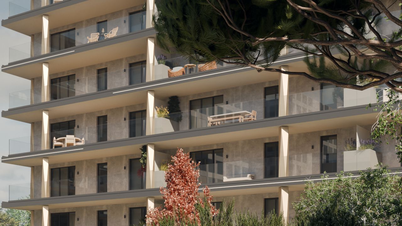 Balcoane ale clădirii B2 cu coloane fațetate în nuanță șampanie, canturi de placă antracit și balustrade din sticlă transparentă, cu mobilier de exterior; dedesubt, un copac cu frunze roșii.